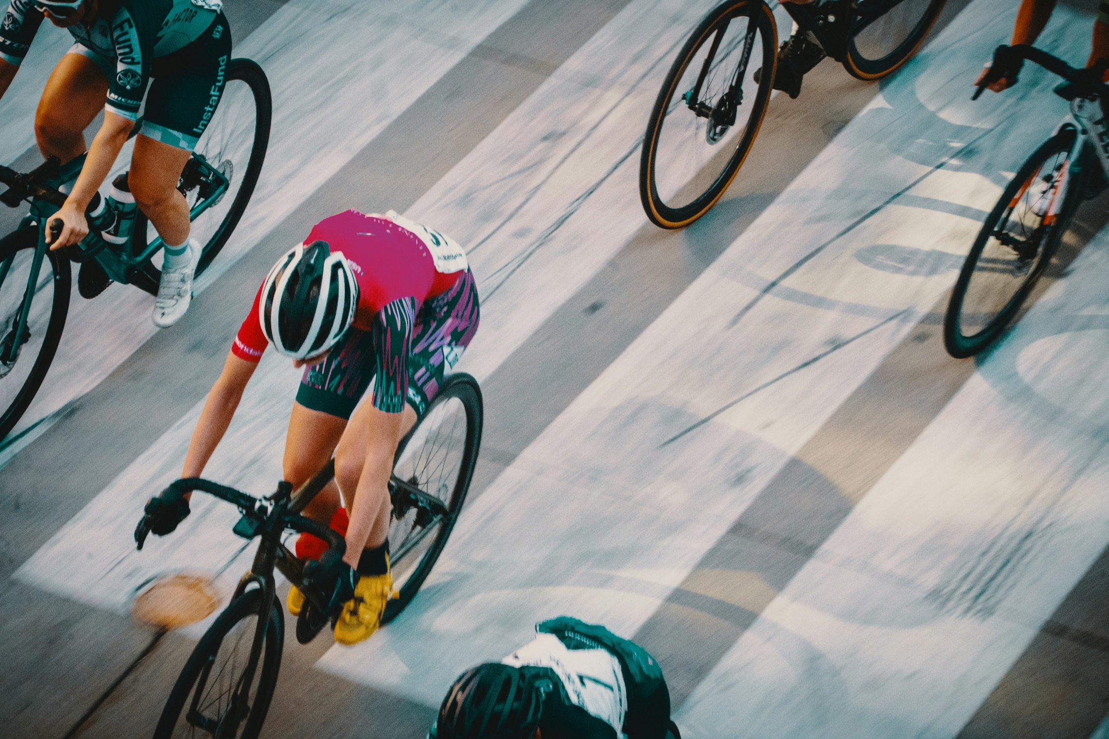 An overhead view of cyclists racing across a sunlit road.