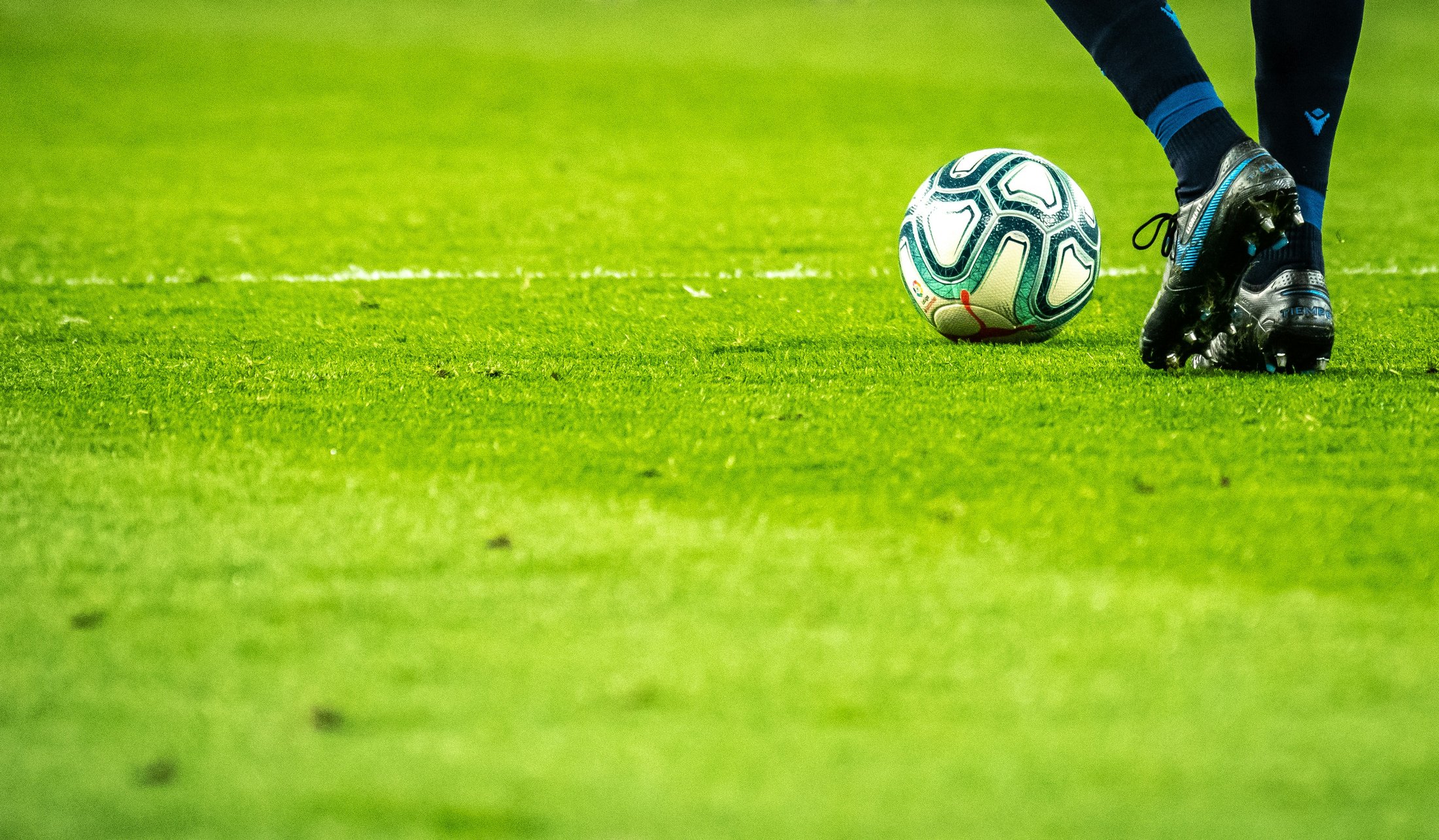 Football and player’s boots on the pitch
